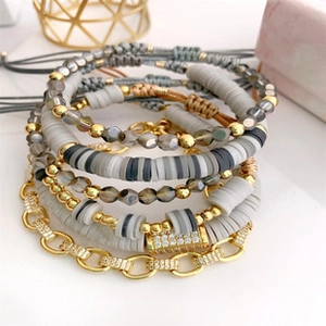Detail of bohemian layered bracelets with grey clay beads and gold zircon chain