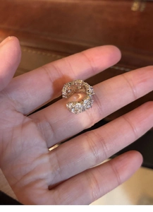 Detailed macro view of silver zircon flower ear cuff held in hand for size visualization