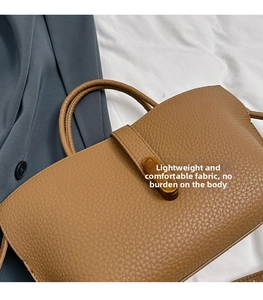 Close-up of brown lychee grain leather handbag with gold turn-lock and dual handles