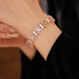 Macro close-up of rose gold bracelet with pink, yellow, and white zircon gemstones on wrist