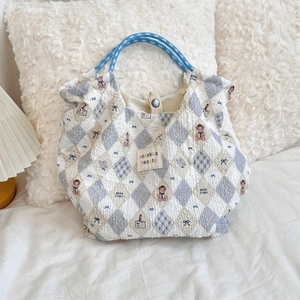 Detail of seersucker tote bag featuring bear patterns and blue rope handles in cozy setting