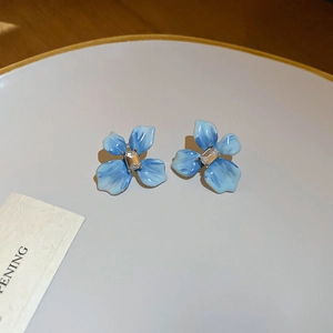 Vue macro de boucles d'oreilles fleur bleue avec pétales dégradés et cristal central