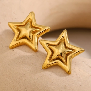 Macro detail of 18K gold plated stainless steel star earrings on stone texture