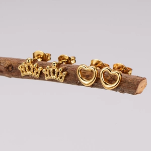 Macro view of gold-plated stainless steel crown and heart stud earrings on a branch