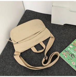 Detailed top view of a beige crescent crossbody bag with adjustable wide strap on felt