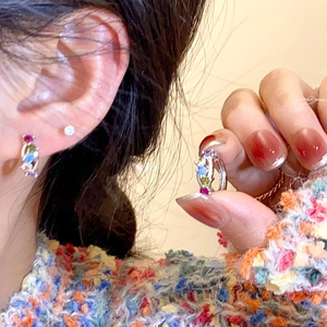 Macro detail of colorful zircon hoop earrings set on a silver rainbow bridge design