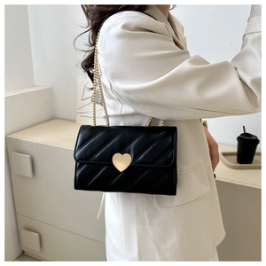 Detail of black quilted leather shoulder bag featuring a golden heart-shaped lock buckle