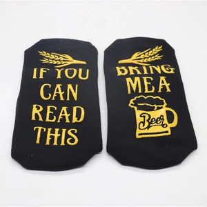 Close-up of black cotton socks with yellow non-slip letter embroidery and beer mug design