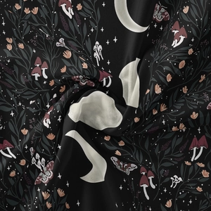 Detail of bohemian tapestry fabric with moon phases, moths, and mushrooms on black