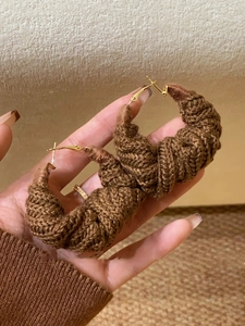 Close-up of brown knit crochet hoop earrings with elegant golden metal clasps