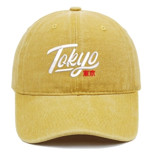 Detailed close-up of Tokyo 3D embroidery on washed yellow cotton baseball cap texture