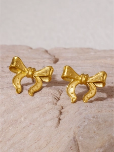 Détail de boucles d'oreilles nœud en or mat avec une texture granulée fine