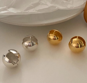 Macro view of minimalist spherical ball earrings in polished silver and gold finishes