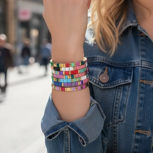 Close-up of stacked colorful Tila bead bracelets with gold accents on model wrist