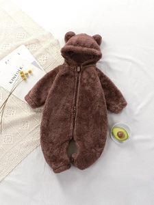 Combinaison bébé en peluche marron avec oreilles d'ours et fermeture sur fond blanc