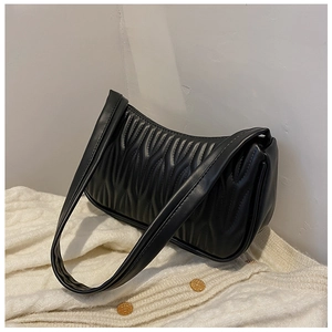 Minimalist black pleated faux leather shoulder bag on a white knitted cardigan