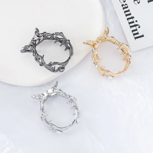 Three metallic thorn-shaped hair claws in black, gold, and silver with rhinestones