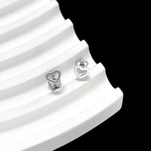 Macro shot of silver minimalist hollow heart stud earrings with petal backings