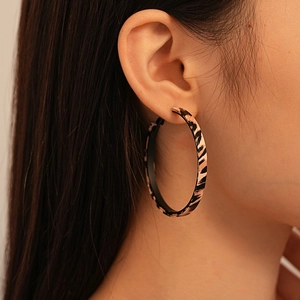 Close-up of oversized leopard print geometric hoop earrings on a fashion model