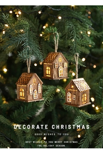 Dettaglio di tre casette in legno a LED appese con calde luci soffuse natalizie