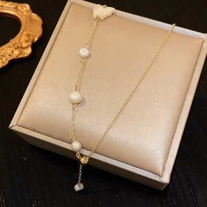 Detailed shot of Baroque freshwater pearl necklace with white butterfly pendant on a beige box