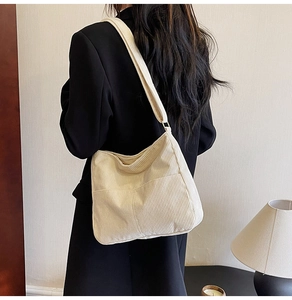 Detail of beige corduroy shoulder bag showing minimalist texture and soft shoulder strap