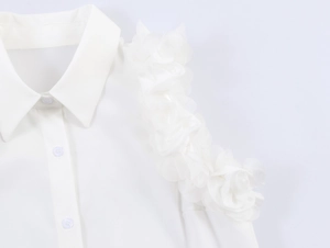 Detail shot of the ruffled floral shoulder accents and button-down collar of a white shirt