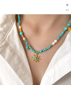 Détail du collier de perles turquoise et perles avec pendentif soleil doré au cou