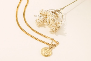 Détail du collier doré avec pendentif arbre de vie et fermoir en T avec fleurs séchées