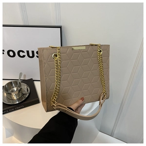 Detail of beige crossbody bag with 3D geometric embossing and gold chain strap