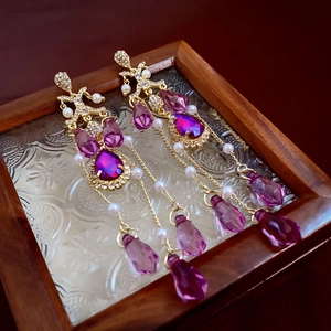 Macro detail of vintage gold earrings with purple crystal teardrops and white pearls