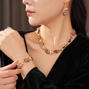 Detail of vintage red enamel and zircon jewelry set worn by a model in soft lighting