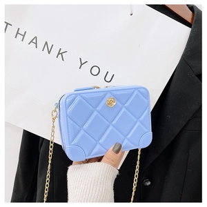 Detail of light blue jelly bag with quilted pattern and gold camellia flower charm