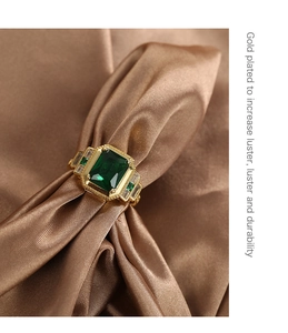 Macro shot of square green zircon ring on brown silk with gold plating detail text