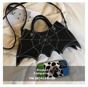 Gothic bat-shaped handbag with spider web stitching shown next to a phone for size comparison