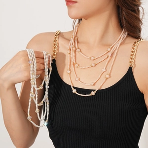 Détail de colliers de perles multicouches en rose et blanc avec perles en cristal
