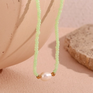 Macro view of a light green beaded necklace featuring a white pearl and gold accents