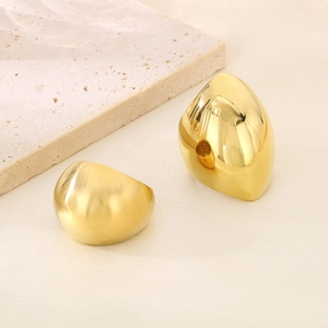 Minimalist golden stainless steel chunky round rings on a natural stone textured background