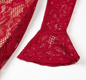 Détail de robe en dentelle rouge avec poignets évasés et motifs ajourés complexes