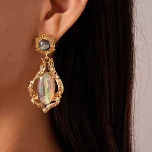 Close-up of vintage golden shell drop earrings with textured metal on a model