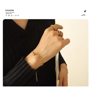 Detail view of double-layer gold lip chain bracelet and textured rings on model