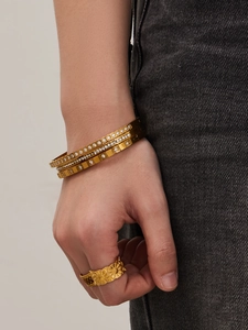 Dettaglio di bracciali in oro con zirconi e un anello vintage con girasole