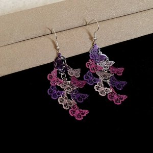 Détail macro de boucles d'oreilles papillon ajourées avec pompons violets et beiges