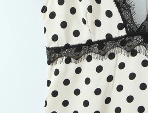 Gros plan d'une robe blanche à pois noirs ornée de dentelle fine noire sur l'encolure