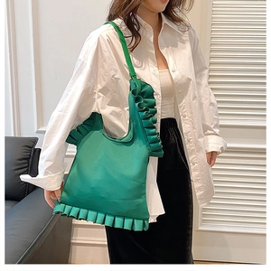 Detail of vibrant green tote bag with ruffled edges worn with casual outfit