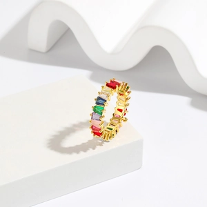 Chic gold ring set with multi-color rectangular gemstones on a white geometric stand