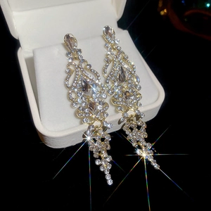 Detailed close-up of sparkling gold drop tassel earrings with zircon in a white gift box
