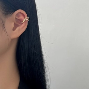 Close-up of minimalist golden ear bone clip with elegant wavy texture on the ear