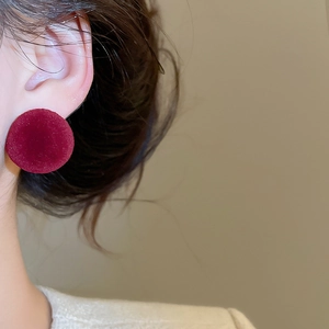 Close-up of model wearing round burgundy flocked velvet stud earrings for autumn style
