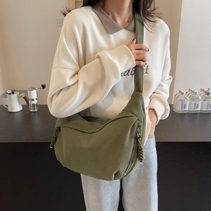 Green corduroy dumpling crossbody bag with woven knot detail shown on a model